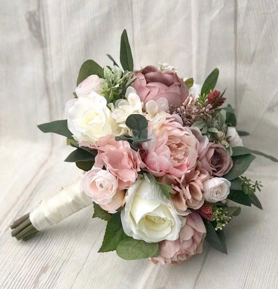 a bridal bouquet with pink and white flowers on a white tableclothed background