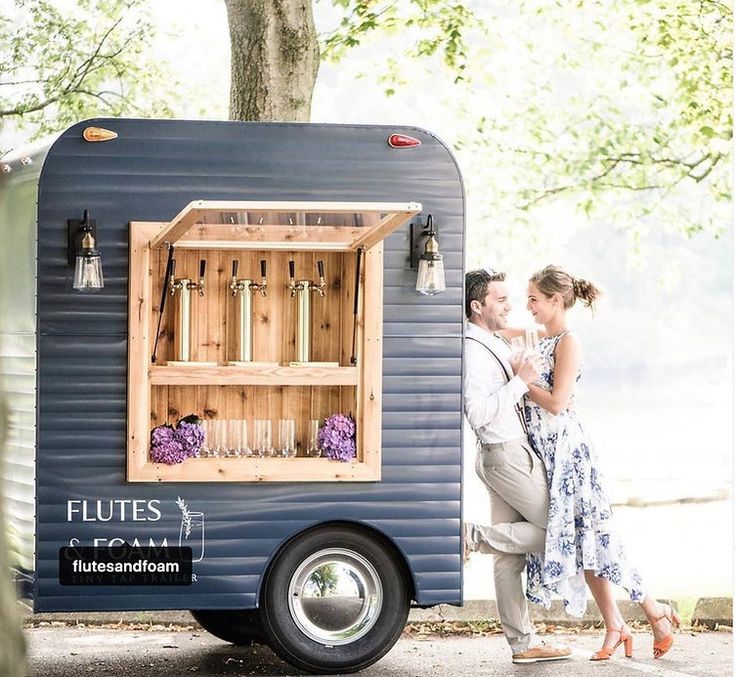 a man and woman are standing in front of a blue trailer that is built into the ground