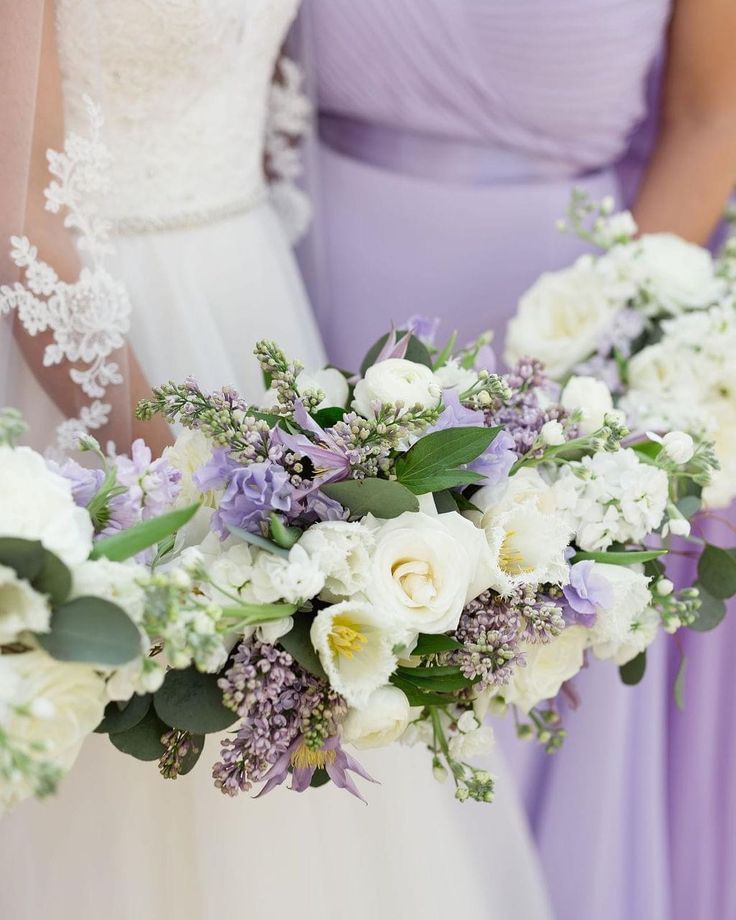 two bridesmaids holding bouquets of white and purple flowers