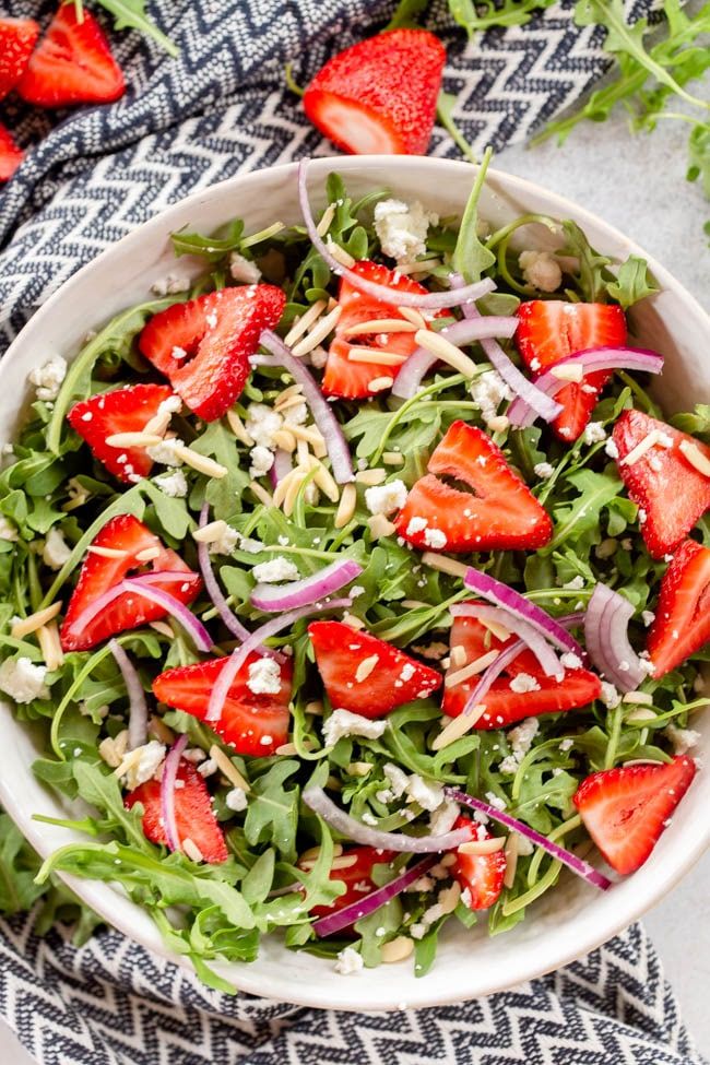 strawberry arugula salad in a white bowl