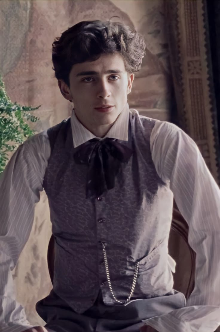 a young man sitting on top of a wooden chair wearing a bow tie and vest