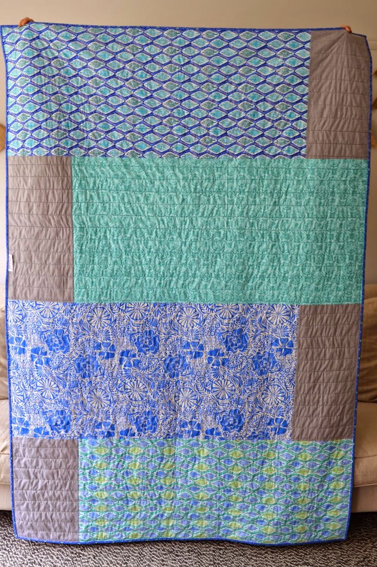 a blue and green quilt sitting on top of a couch