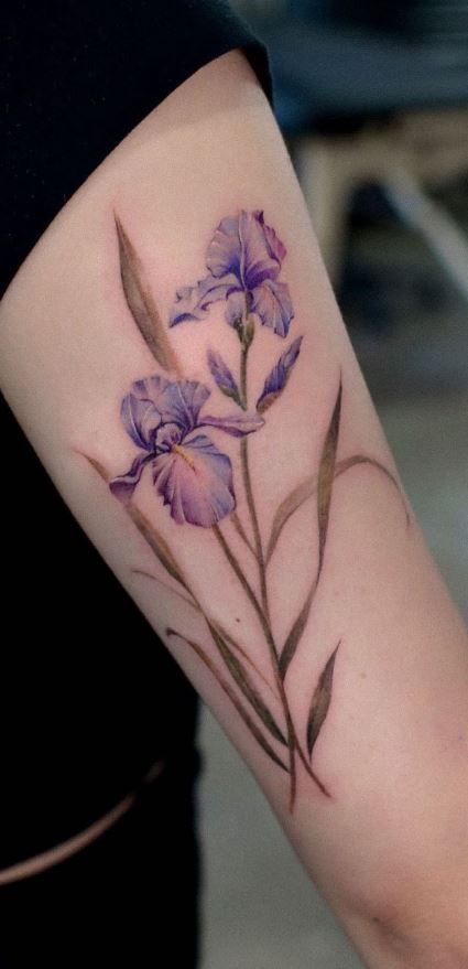 a woman's arm with purple flowers and leaves on the left side of her arm