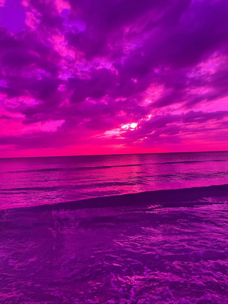 the sun is setting over the ocean with purple clouds