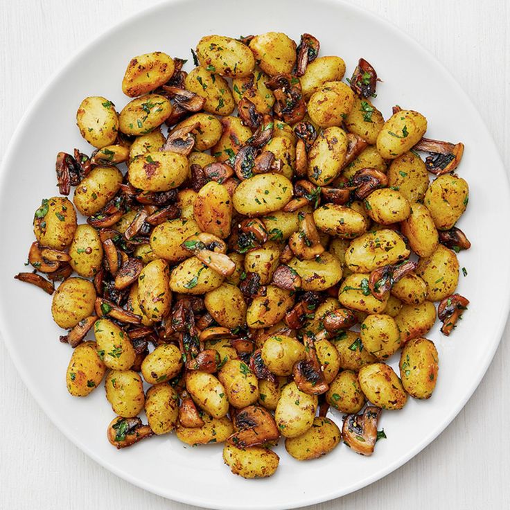 a white plate topped with cooked potatoes and mushrooms