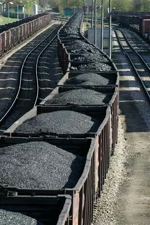 the train is traveling down the tracks with coal in it's containers on either side