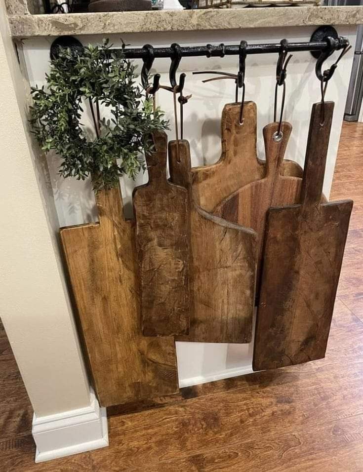 several wooden cutting boards are hanging on a rack in the middle of a kitchen area