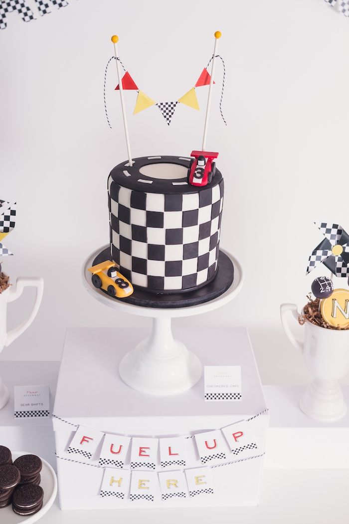 a black and white cake sitting on top of a table next to cupcakes