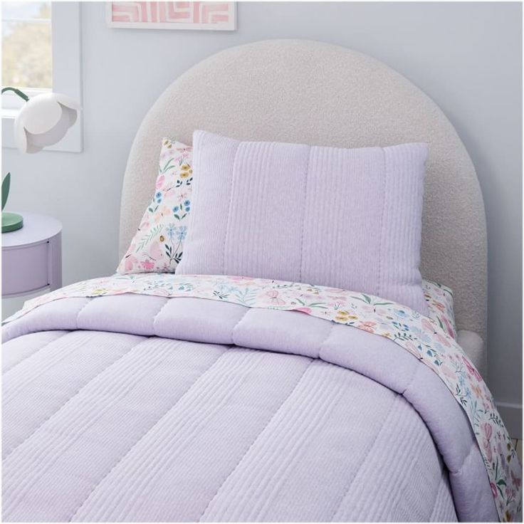 a white bed with purple comforter and pillows