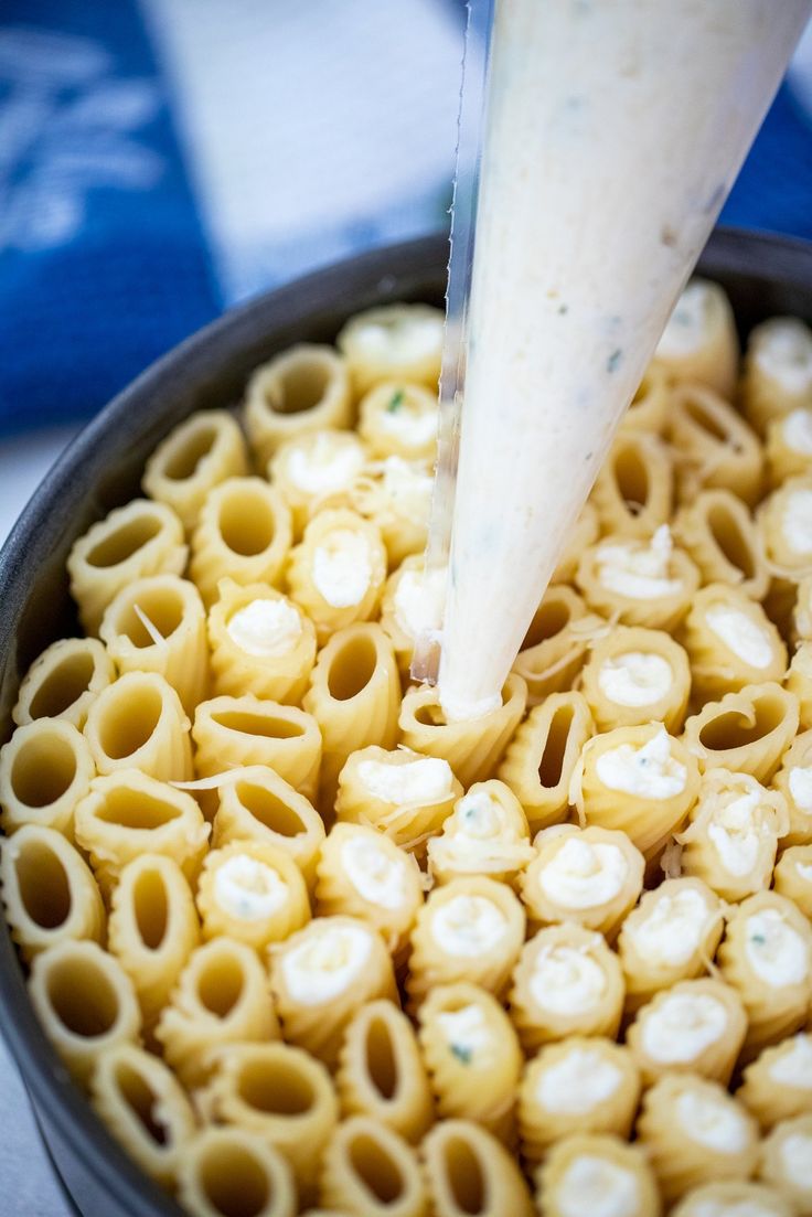 a bowl filled with macaroni and cheese being piped into the cream sauce