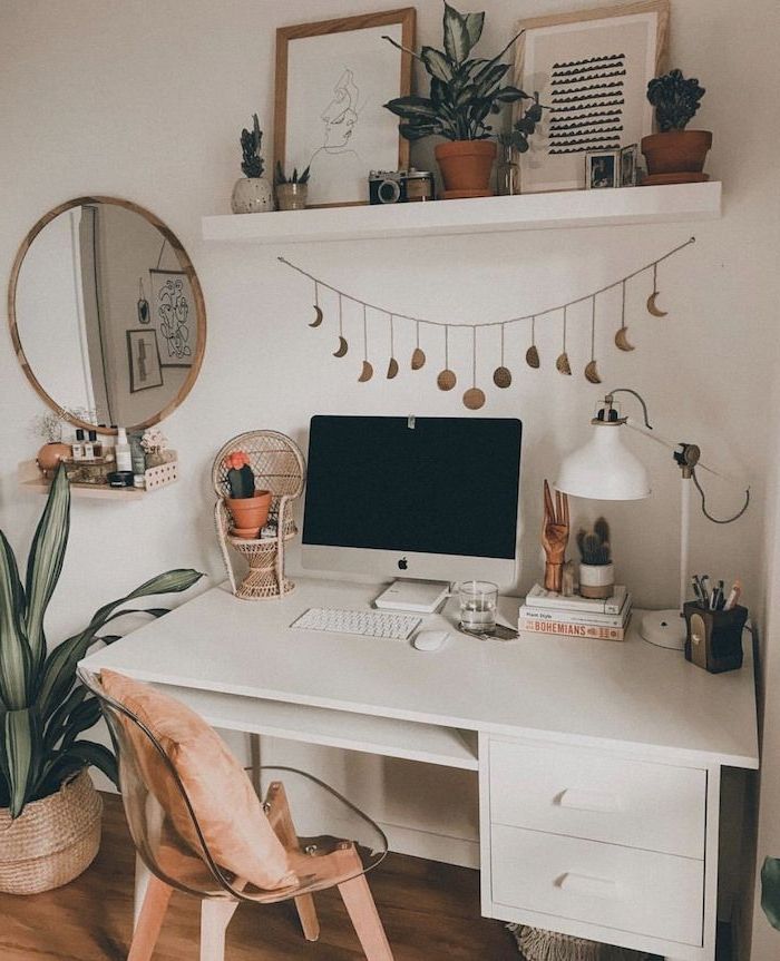 a white desk topped with a computer monitor next to a wooden chair and potted plant