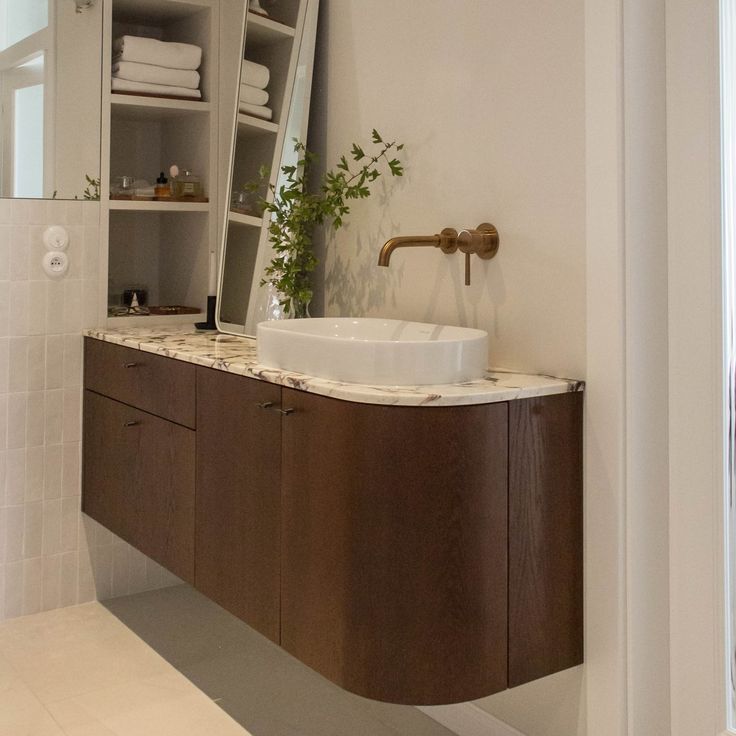 a bathroom with a sink, mirror and shelves