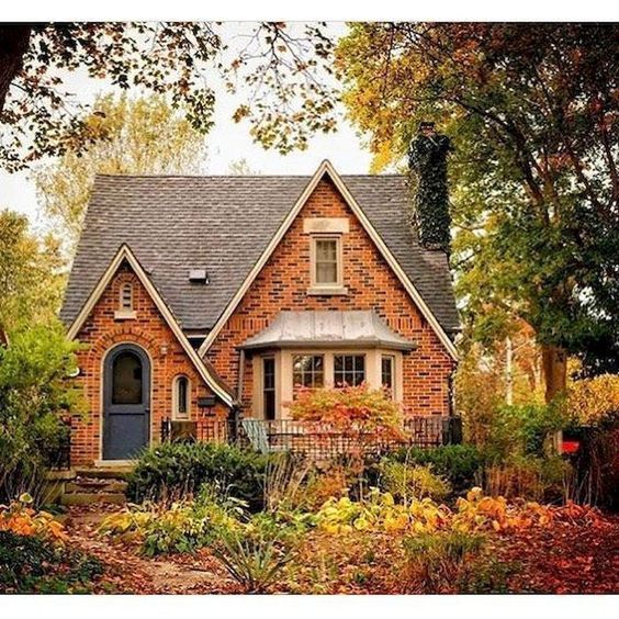 a red brick house surrounded by trees and flowers in the fall season, with autumn foliage surrounding it