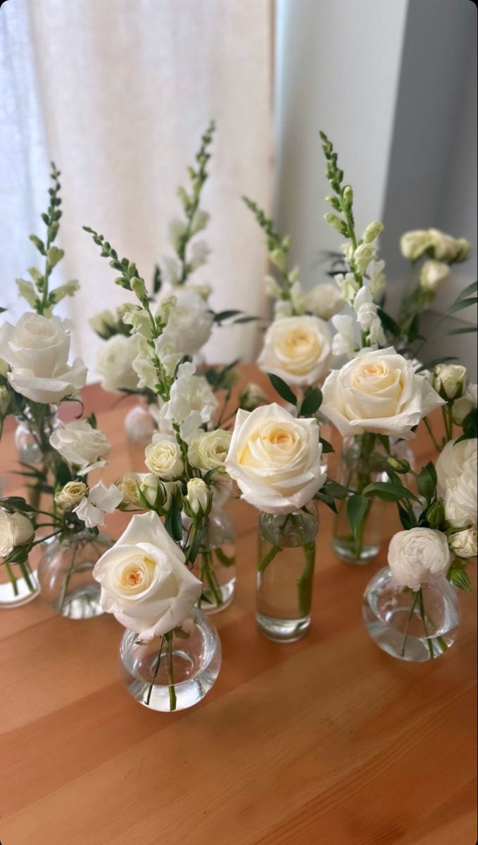 there are many white flowers in vases on the table