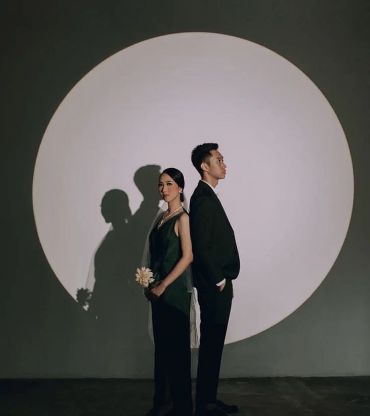 a man and woman standing in front of a wall with a large shadow on it