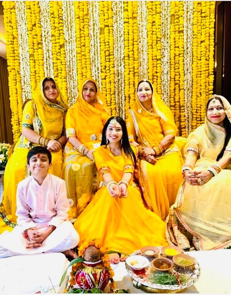 a group of people sitting next to each other in front of a yellow wall with flowers