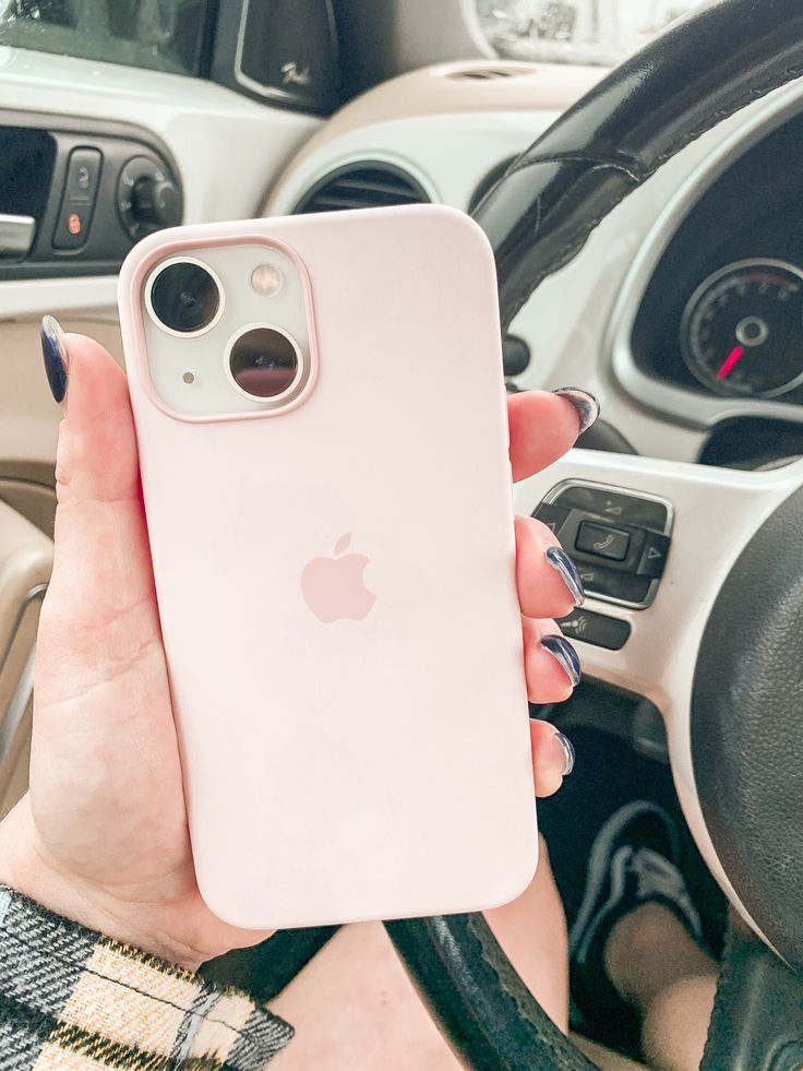 a person holding an iphone in their hand while sitting in the driver's seat