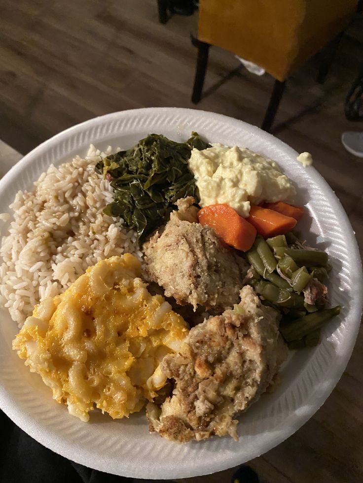 a white paper plate filled with different types of food on top of a wooden table