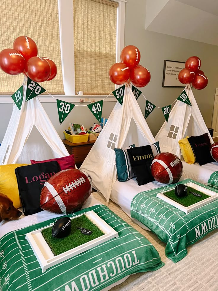 two beds with football themed pillows and teepees on them in a room decorated for sports season