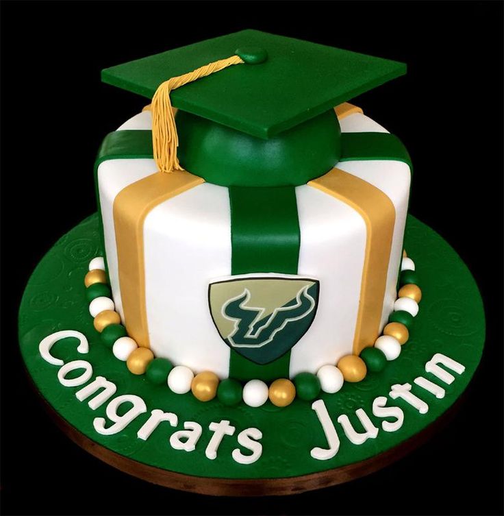 a green and white graduation cake with gold accents