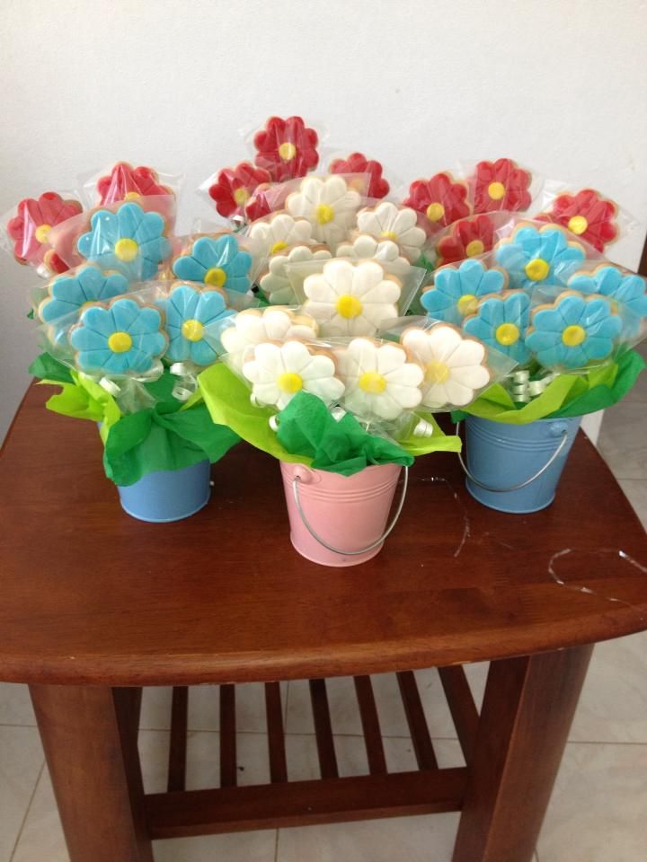 colorful flowers are sitting in blue and white buckets on a small wooden table with tile flooring