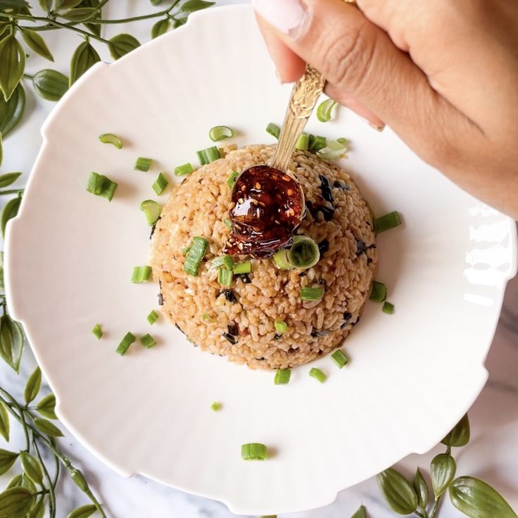 someone is dipping sauce on top of a rice dish