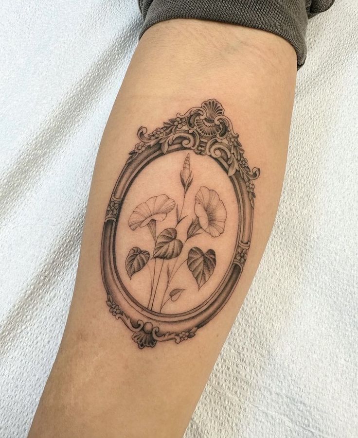 a woman's arm with a tattoo on it that has flowers in the frame