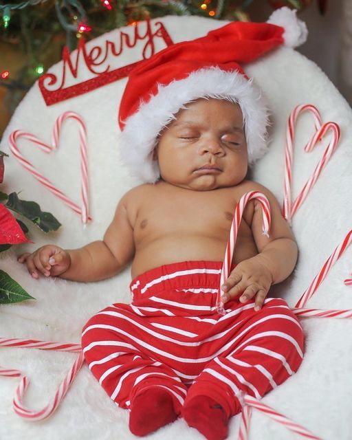 a baby wearing a santa hat and holding a candy cane