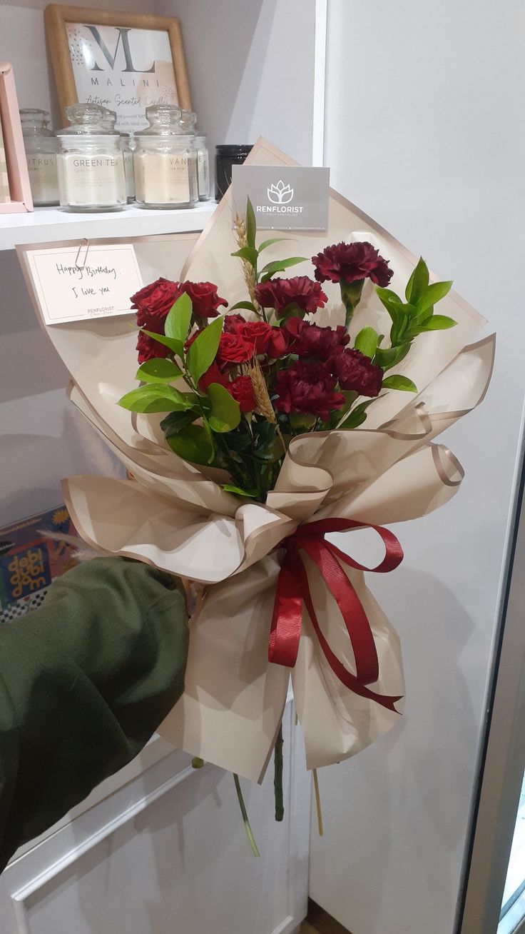 a bouquet of red flowers sitting on top of a white doorknob next to a window