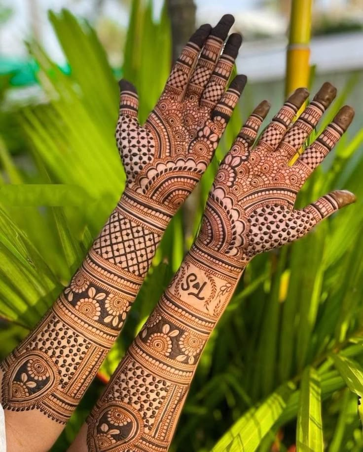 two hands with henna tattoos on them and palm trees in the back ground behind them