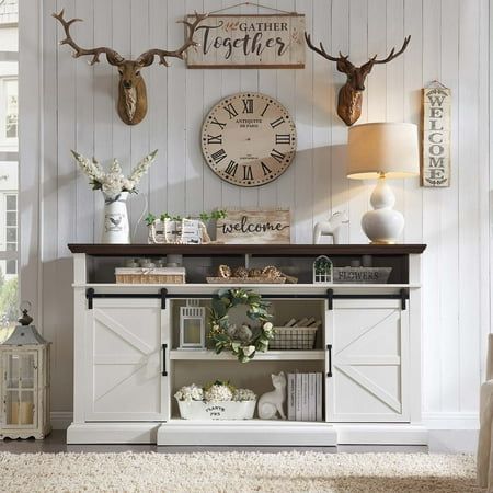 a living room with white furniture and deer heads on the wall above it's fireplace