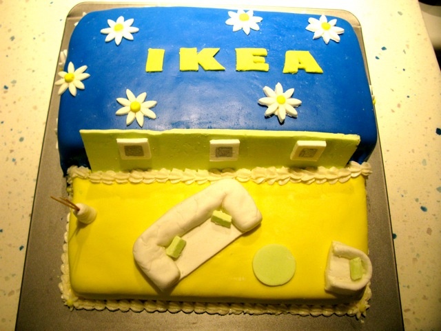 there is a blue and yellow cake that says ikea on the side, with white flowers