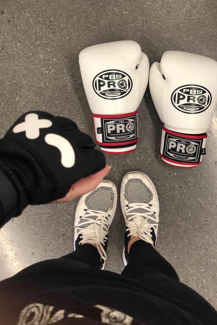 a person wearing white and black boxing gloves with their feet propped up on the ground