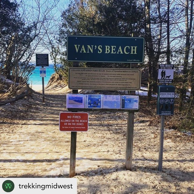 a sign that says van's beach on the side of a dirt road with trees in the background