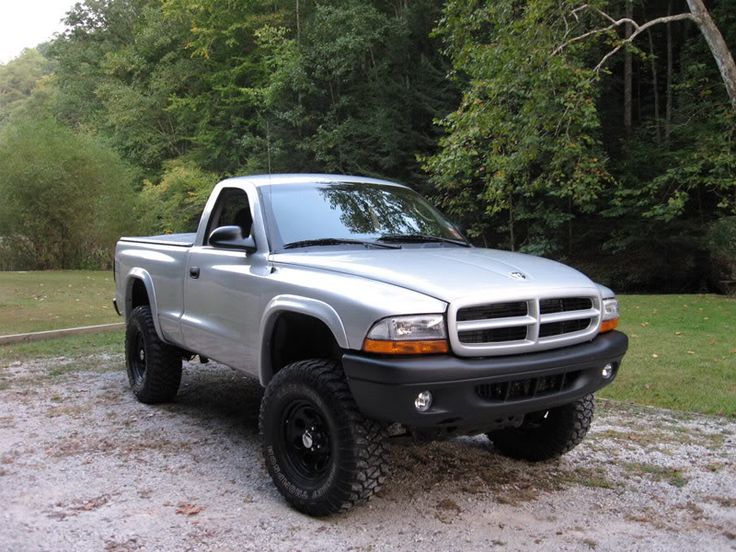 a silver truck parked on top of a gravel road