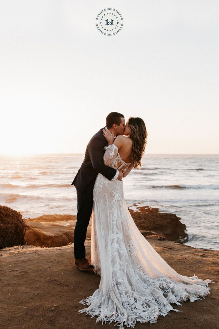 a bride and groom kissing on the beach in front of the ocean at their wedding