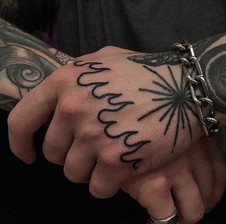 a man with tattoos on his arm and wrist is holding the hand of another person