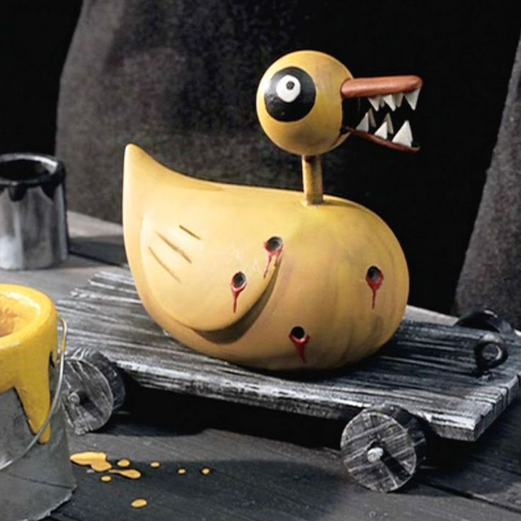 an odd looking yellow object sitting on top of a wooden table next to a cup