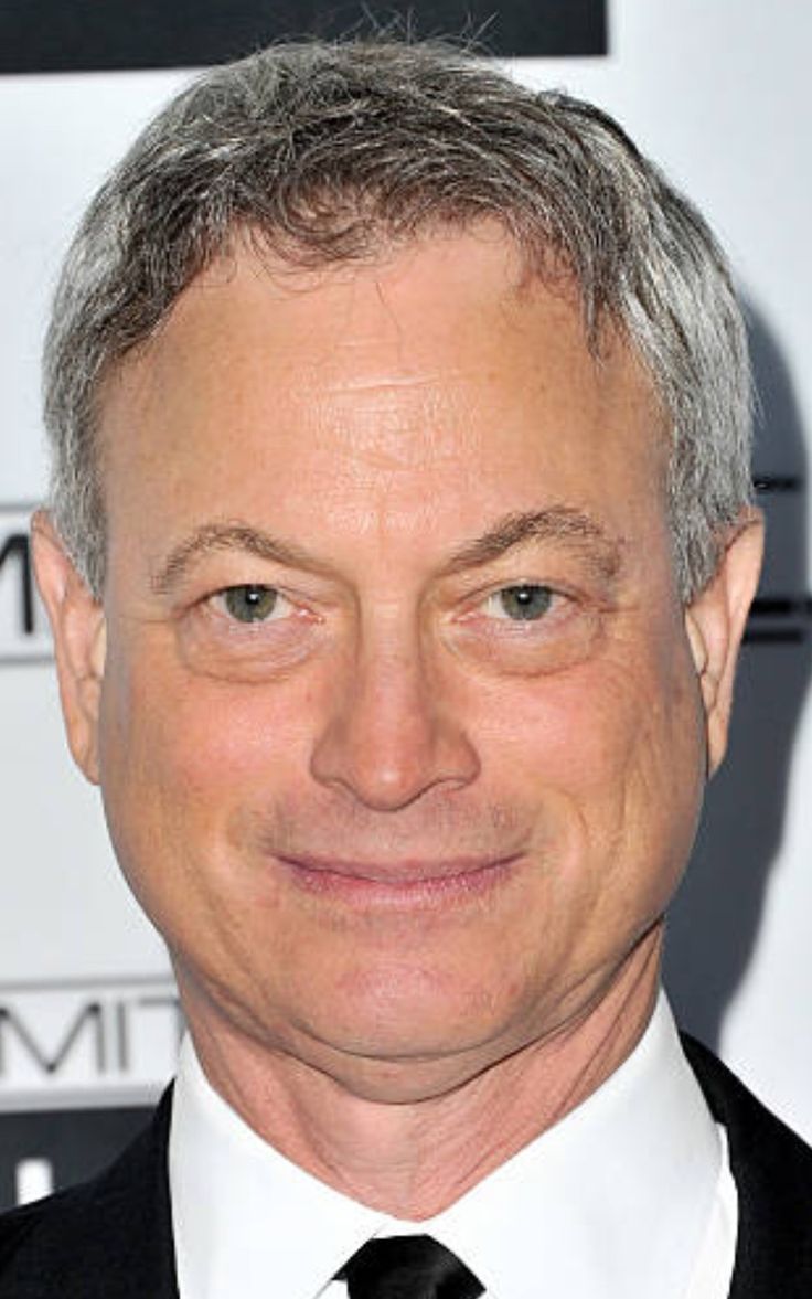 a close up of a person wearing a suit and tie with a smile on his face