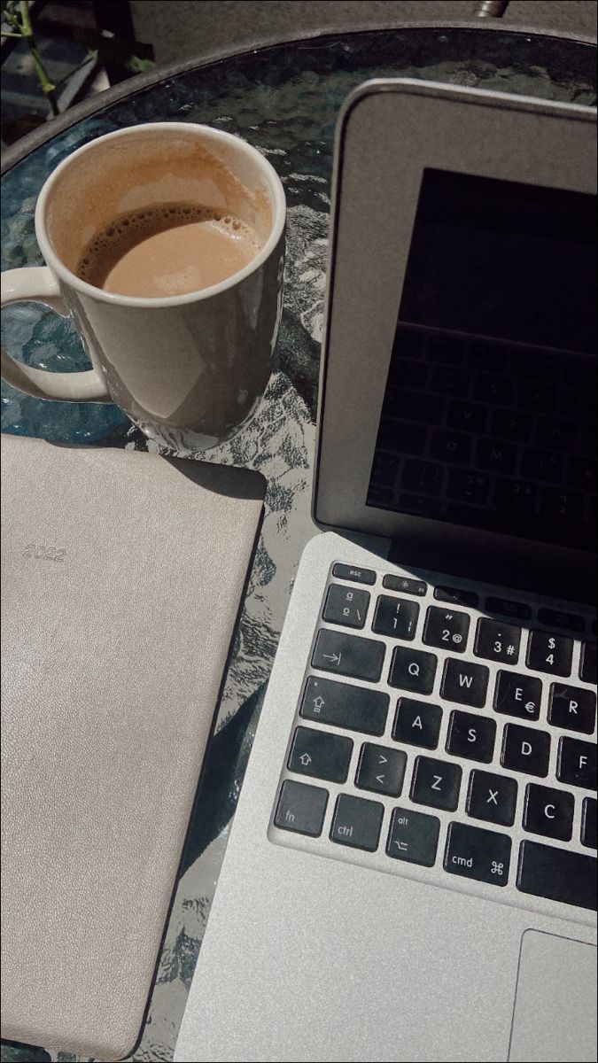 an open laptop computer sitting on top of a table next to a cup of coffee