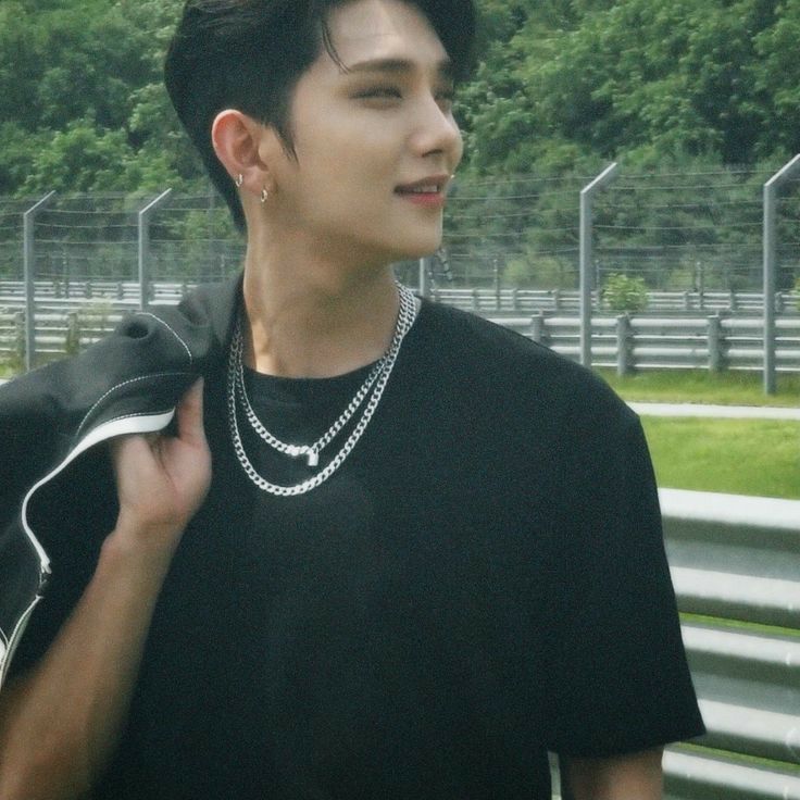 a young man wearing a black shirt and silver necklace