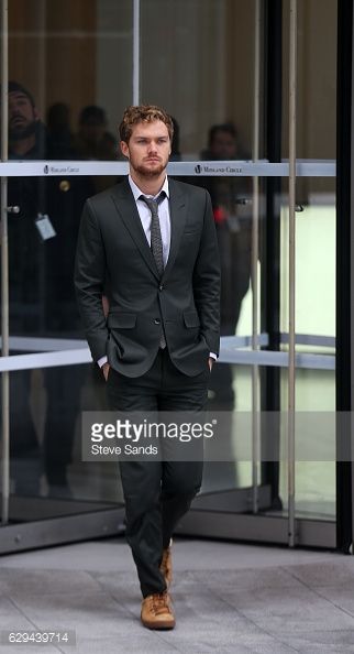 a man in a suit and tie walking down the street with his hands in his pockets