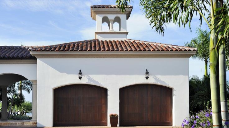 two brown garage doors in front of a white house