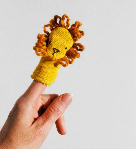 a hand holding up a small toy with a lion on it's head