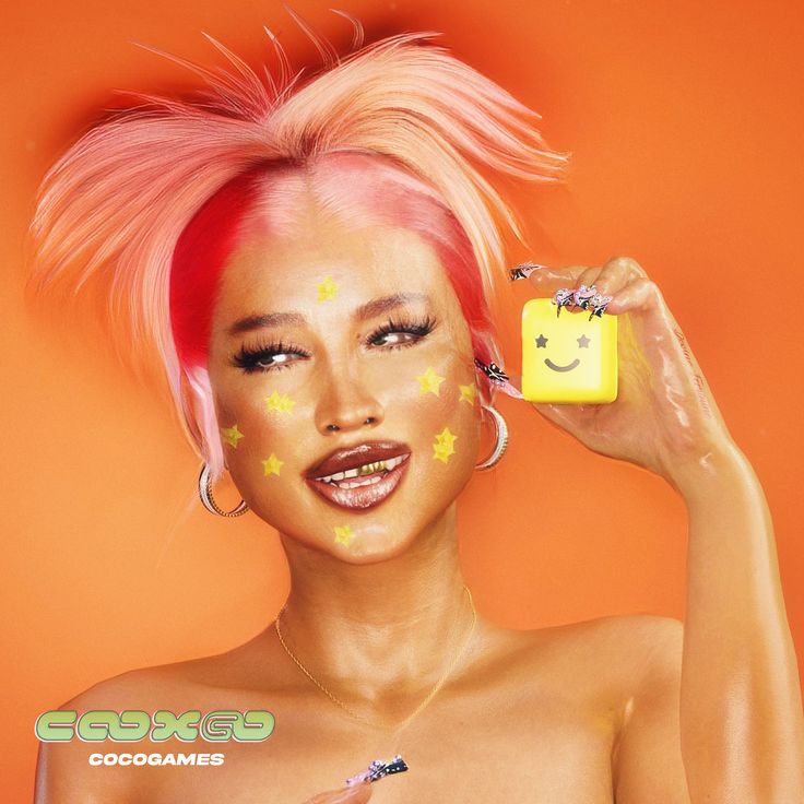 a woman with pink hair holding up a yellow object in front of her face and smiling