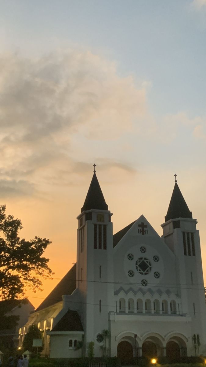 a large white church with two towers at sunset