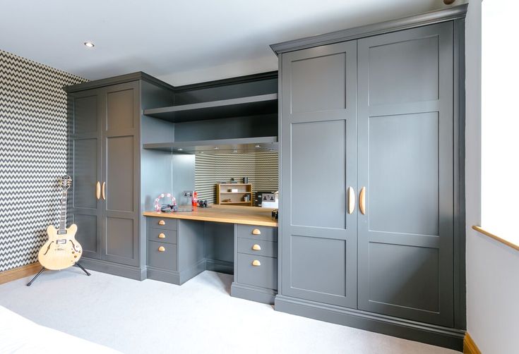 a bedroom with gray cabinets and white carpeted flooring on the side walk in closet