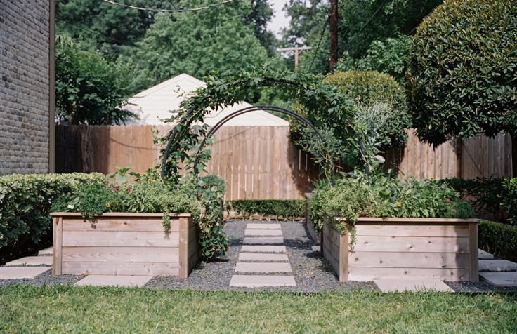 an outdoor garden with wooden planters and steps leading up to the back yard area