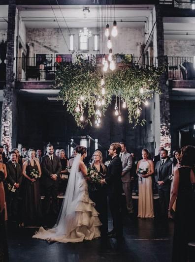 a bride and groom standing in front of their wedding party at the end of an aisle