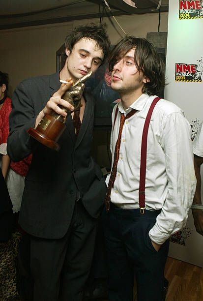 two young men standing next to each other holding an award in their hands and looking at the camera